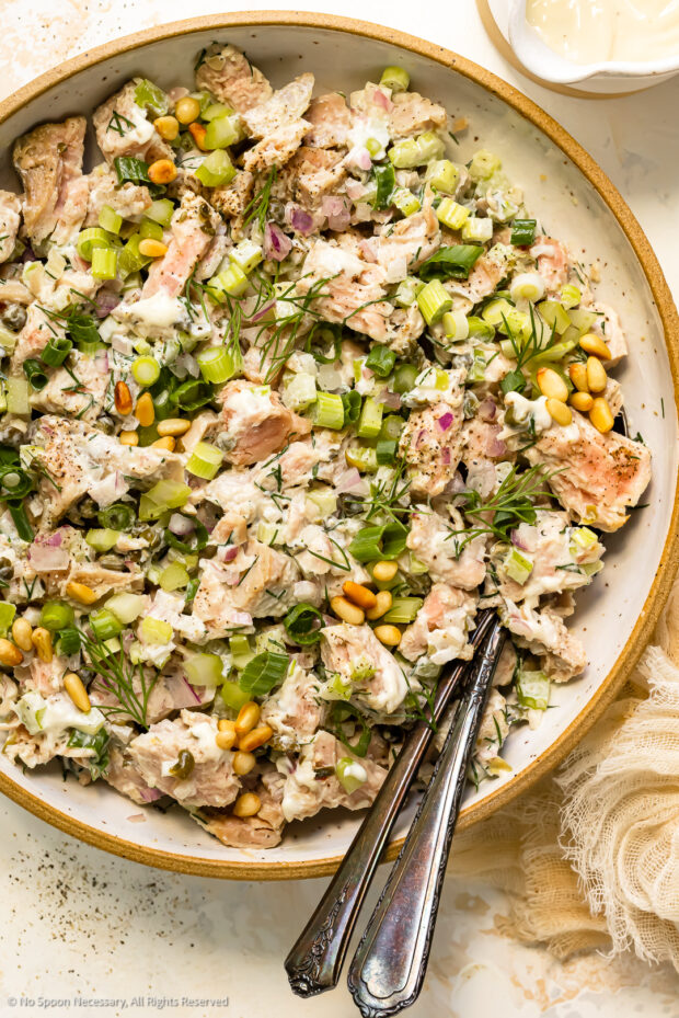 Overhead photo of fresh tuna salad with vegetables and creamy dressing in a white serving bowl.