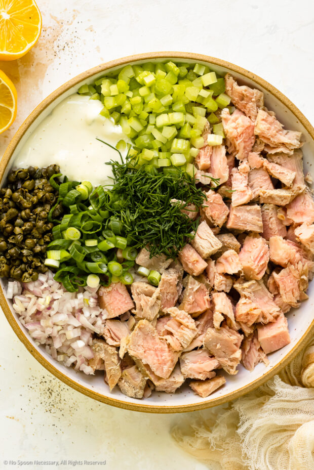Overhead photo of tuna salad ingredients in a mixing bowl before being tossed together.