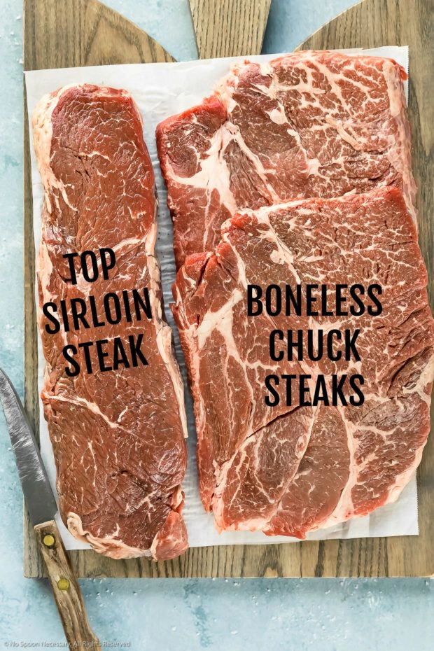 Overhead shot of a parchment paper lined gray wood board topped with a sirloin steak and boneless chuck steaks - photo of the two cuts of beef to use in homemade burger meat.