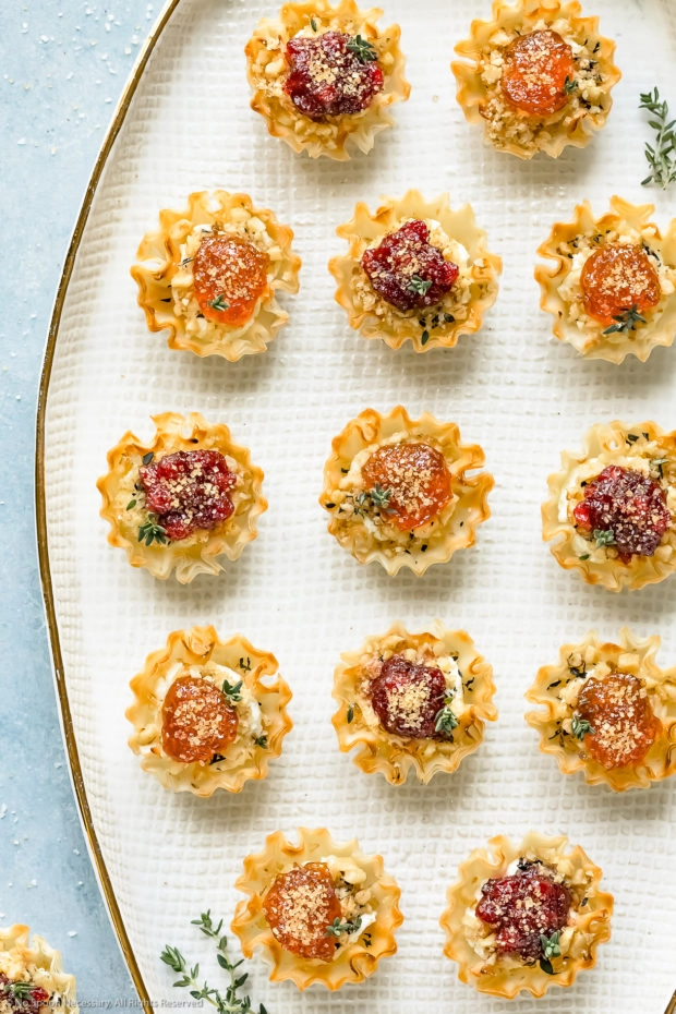 Overhead photo of Goat Cheese Phyllo Cup Appetizers topped with jam on a white platter.