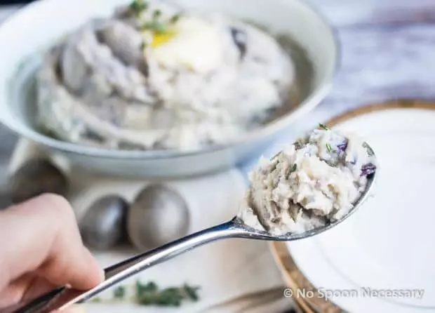 Closeup of purple mashed potatoes on a spoon.