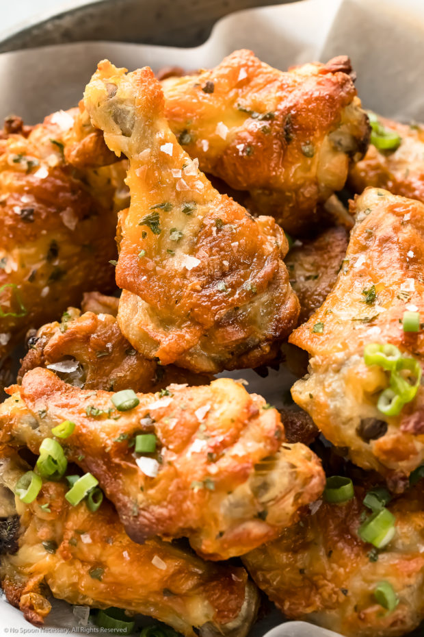 Angled, upclose photo of baked salt and vinegar wings garnished with flaky sea salt and sliced scallions.