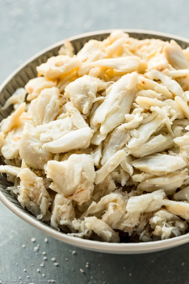 Angled, close-up photo of fresh lump crab in white bowl.