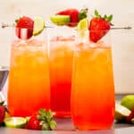 Photo of three alcoholic drinks with strawberries in tall glasses.
