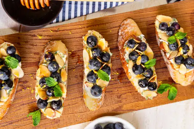 Overhead photo of four slices of toast with blueberries and ricotta.