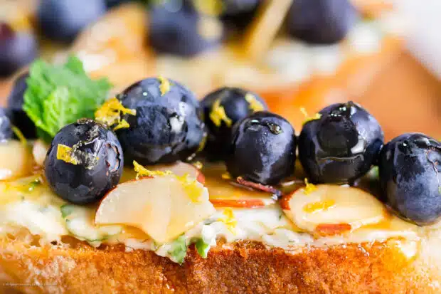 Close-up photo of whipped ricotta toast with fresh blueberries and honey.