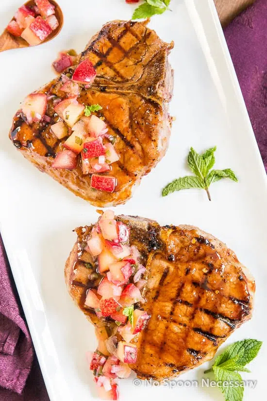 grill pork chops with plum salsa on white platter