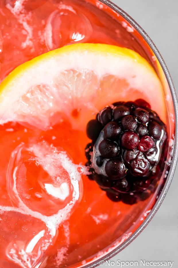 Overhead, up-close shot of a Blackberry Bramble Cocktail Recipe in a rocks glass garnished with a blackberry and lemon slice.