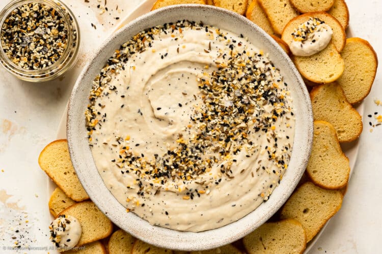 Overhead photo of a platter containing bagel dip topped with everything spice and bagel chips.