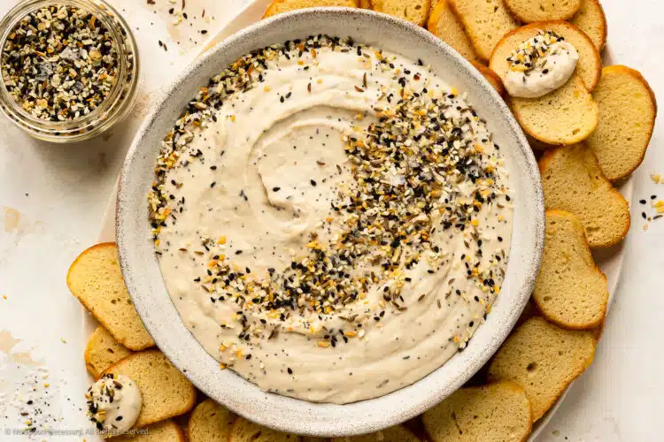 Overhead photo of a platter containing bagel dip topped with everything spice and bagel chips.