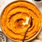 Overhead photo of butternut squash mash with a pat of butter in a white serving bowl.
