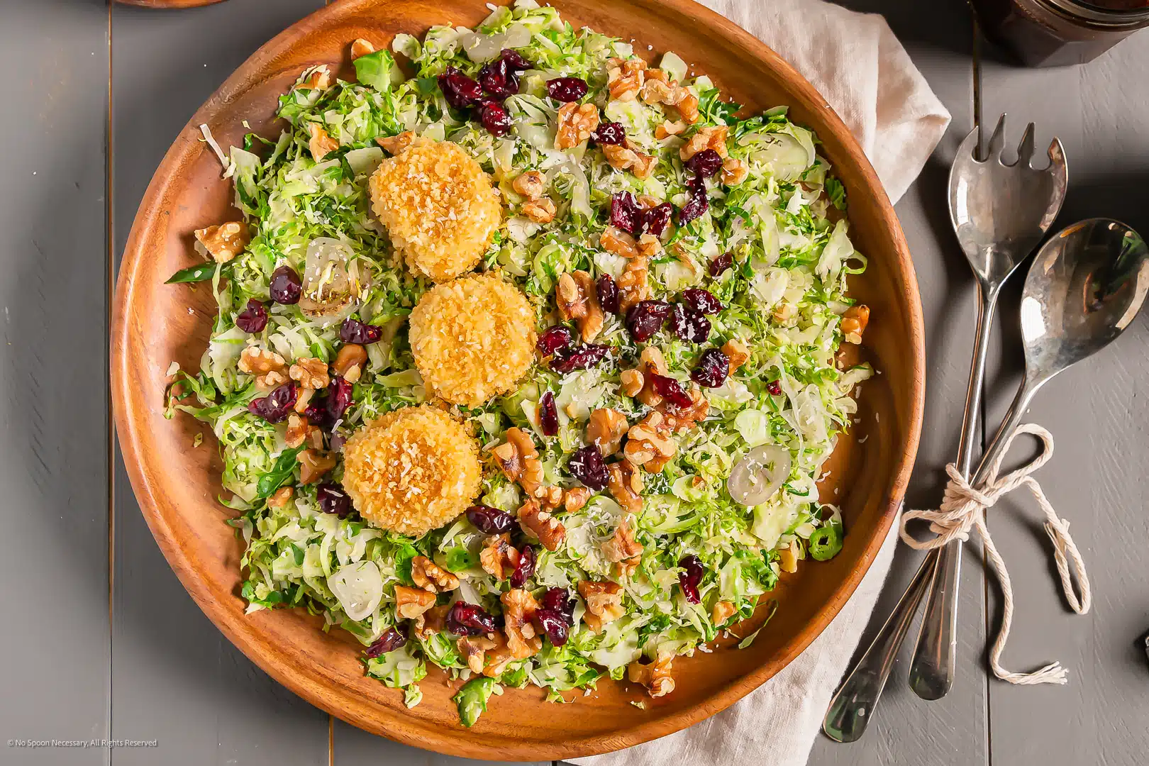 Overhead photo of a shaved brussels sprouts salad with cranberries, walnuts and baked goat cheese.