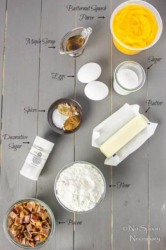 Overhead shot of all the ingredients needed to make Bacon Butternut Squash Scones recipe neatly organized on a gray wood surface with the name of each individual ingredient pointing to the ingredient.