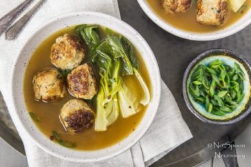 Overheat shot of a bowl of Ginger Chicken Meatball Miso Soup and Bok choy with a ramekin of sliced scallions, neutral linen and additional bowl of soup off to the side.