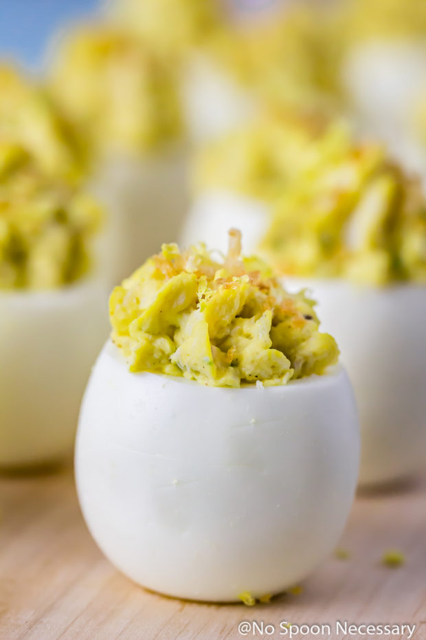 Straight on shot of a Crab Cake Deviled Egg with more deviled eggs blurred in the background.