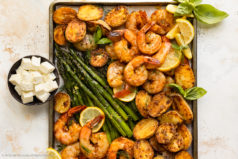 Overhead landscape photo of shrimp sheet pan dinner with potatoes, asparagus and lemon wedges.