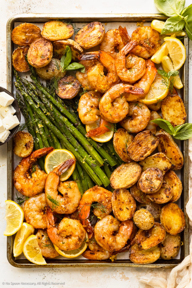 Overhead photo of roasted shrimp and potatoes with asparagus on a sheet pan.