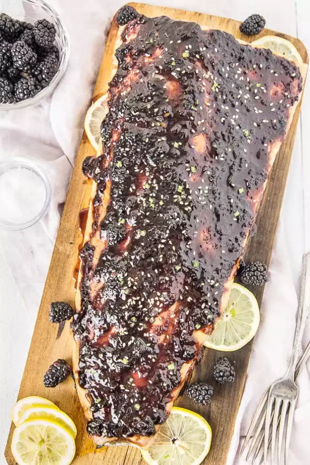 cedar plank salmon garnished with lemon slices and fresh blackberries