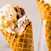 Close-up photo of a scoop of buttered pecan ice cream in a waffle cone.