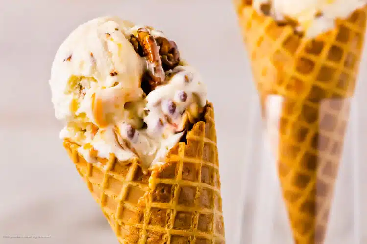 Close-up photo of a scoop of buttered pecan ice cream in a waffle cone.