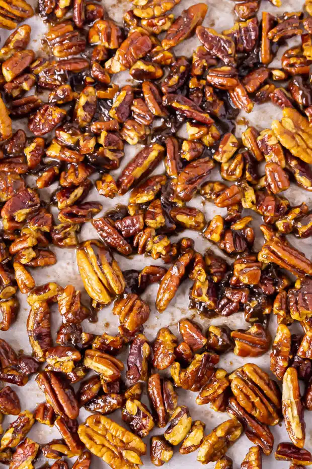 Close-up photo of buttered pecans on a piece of parchment paper.