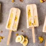 Overhead photo of four banana popsicles laying on a counter.