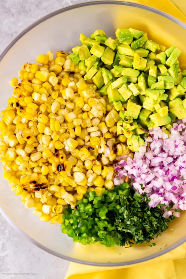 Overhead photo of all the ingredients for corn avocado salsa in a mixing bowl.