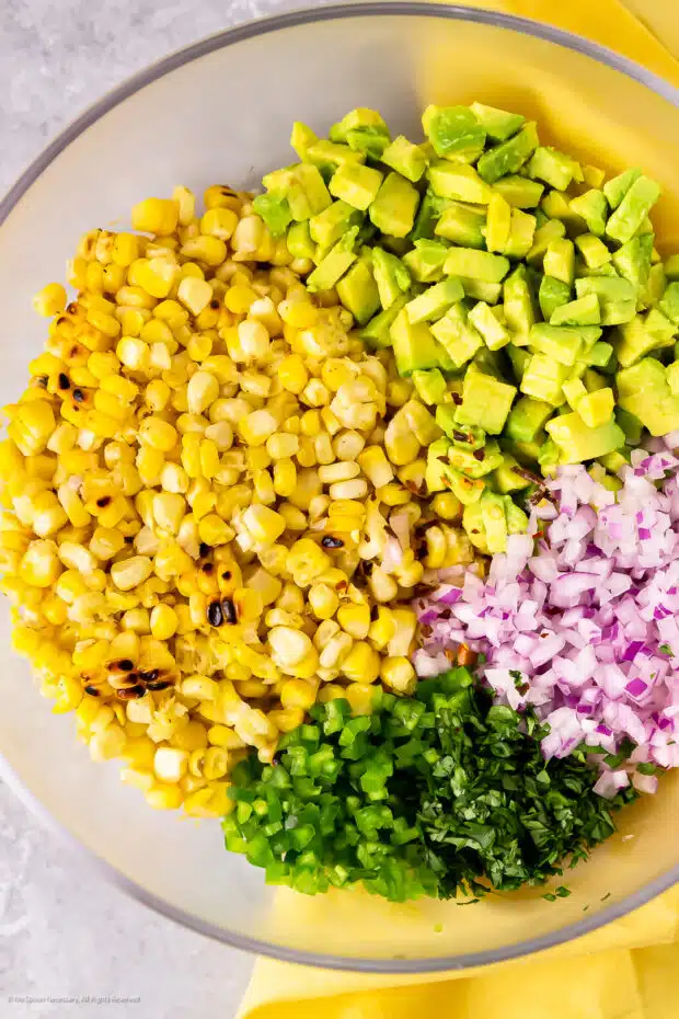 Overhead photo of all the ingredients for corn avocado salsa in a mixing bowl.