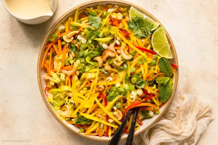 Overhead photo of Thai mango salad with coconut lime dressing in a white serving bowl.