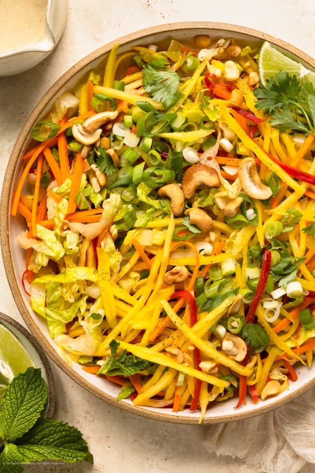 Overhead photo of a thai salad with mango, bell pepper, carrot, and a lime coconut dressing.