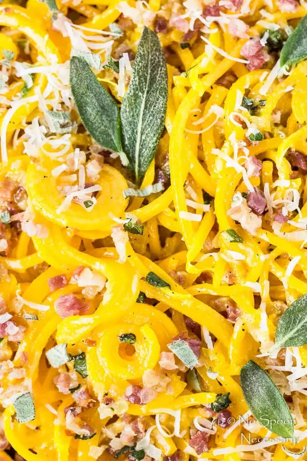 Overhead, extremely up-close shot of Butternut Squash Noodle Carbonara garnished with fresh parmesan and crispy sage leaves.