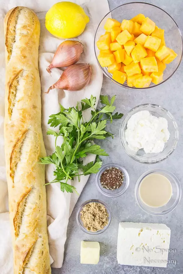 All the ingredients needed to make Caramelized Butternut Squash Crostini neatly organized with a neutral linen on a gray surface.