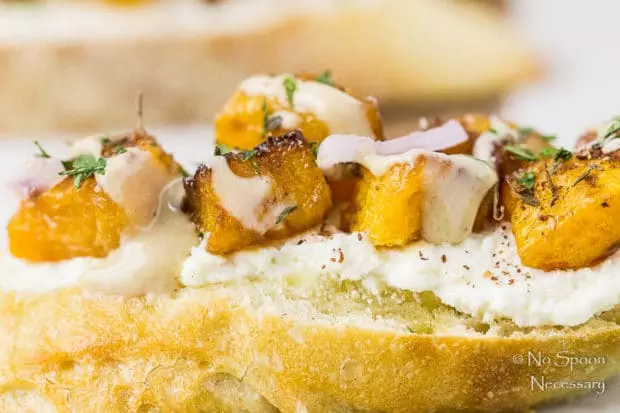 Straight on, up close shot of a Caramelized Butternut Squash Crostini topped with whipped Feta, za'atar and tahini. 
