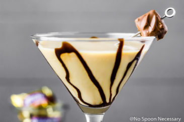 Straight on, up close shot of a Snickers Chocolate Martini garnished with chocolate syrup and a mini snickers.