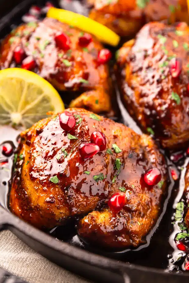 Angled photo showcasing the pomegranate sauce on a cooked chicken thigh.
