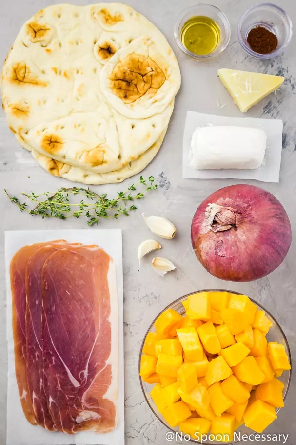 All the ingredients to make Butternut Squash Flatbread pizza neatly laid out on a bluish-gray surface
