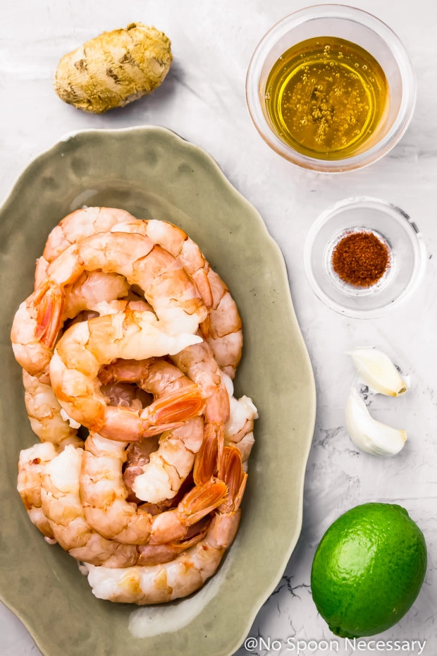 Overhead shot of all the ingredients needed to make Spicy Honey Glazed Skillet Shrimp neatly organized on a bluish-gray surface.
