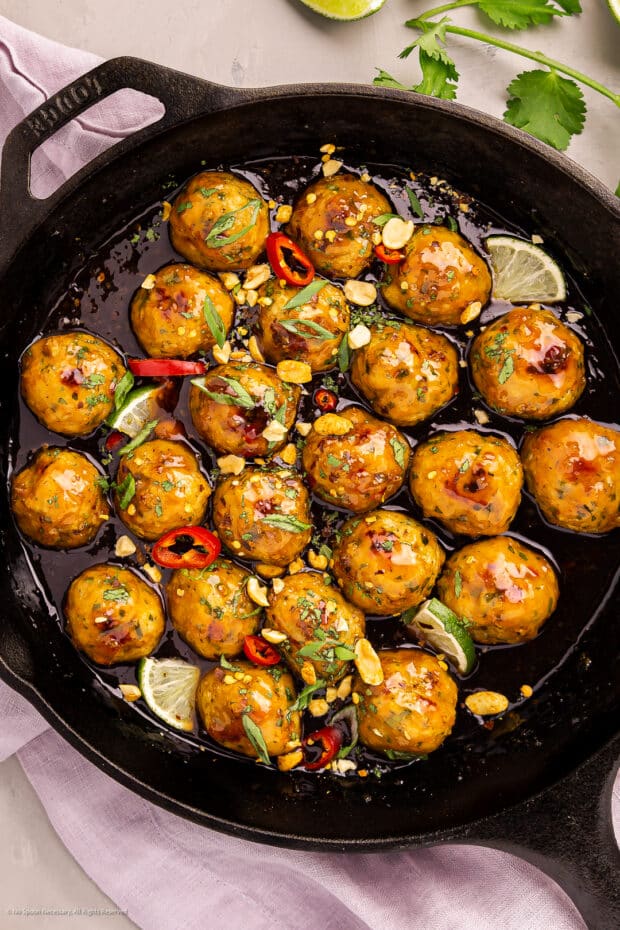 Photo of chicken thai meatballs in a large cast iron skillet.