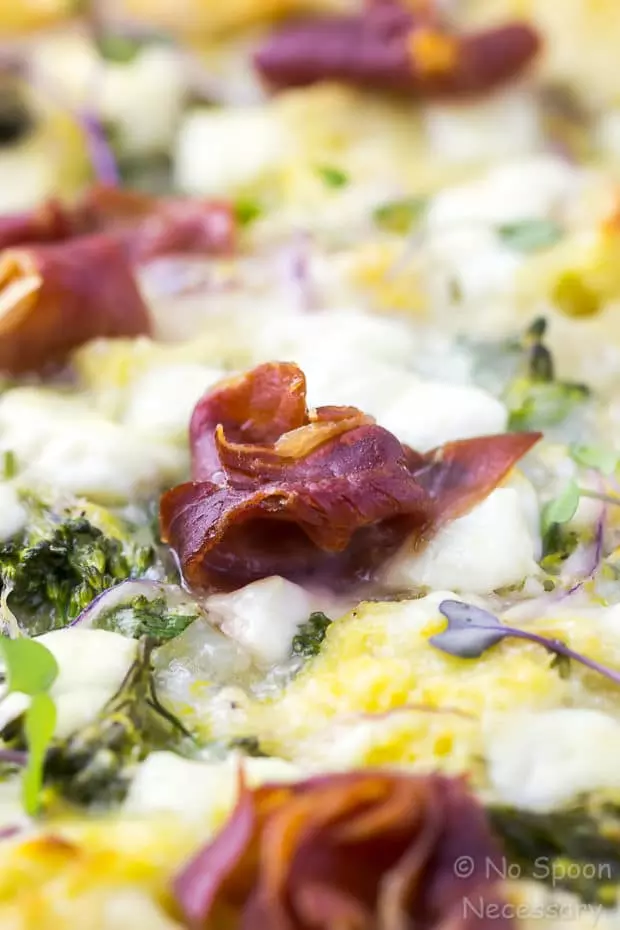 45 degree angle, up-close shot of an Overnight Broccolini & Goat Cheese Strata with Crispy Prosciutto, with the focus of the shot on a crispy prosciutto rose.