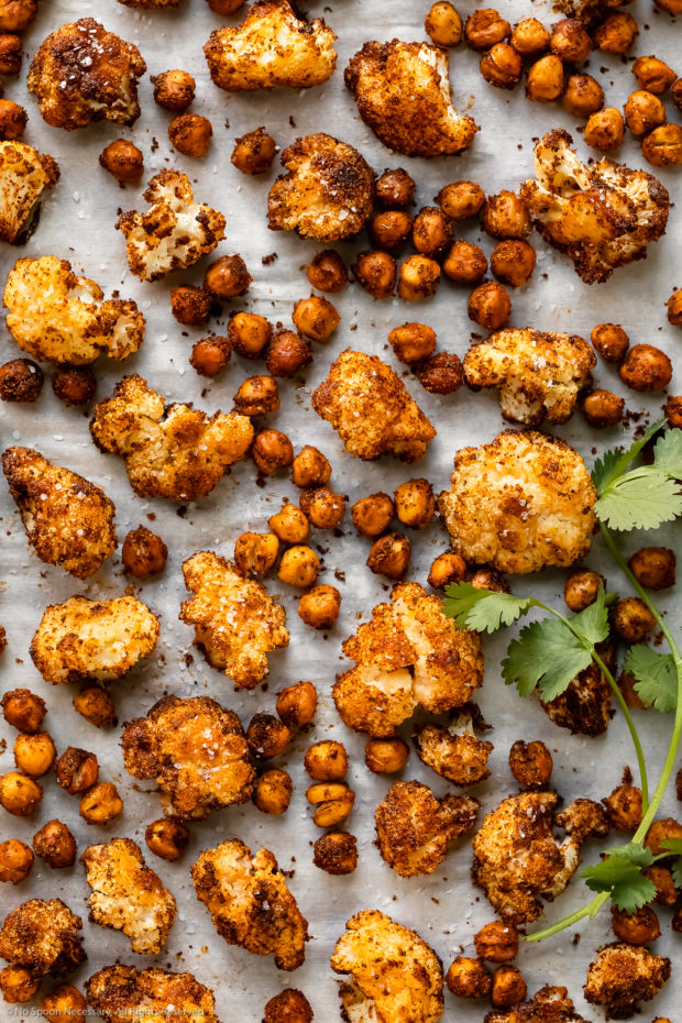 Overhead photo of roasted cauliflower and crispy chickpeas on a parchment paper lined baking pan - photo of the main ingredients in salad recipe.