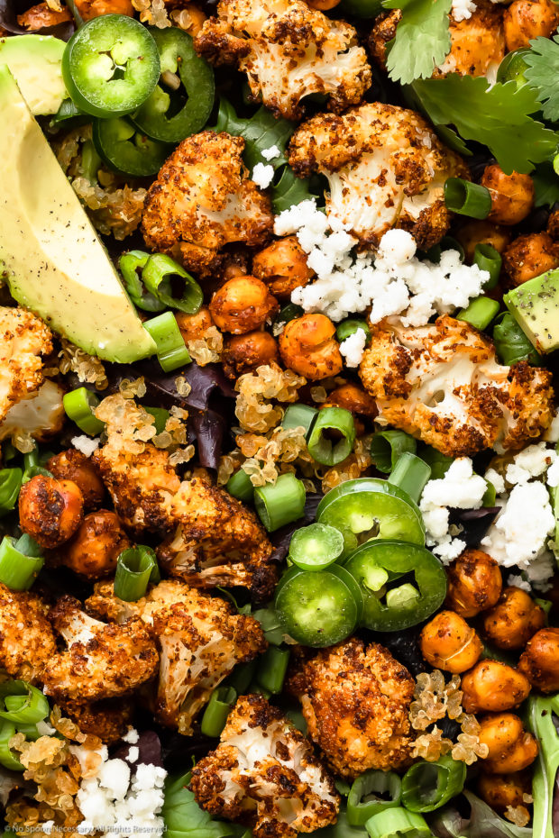 Overhead, close-up photo of roasted cauliflower salad drizzled with homemade avocado dressing. 