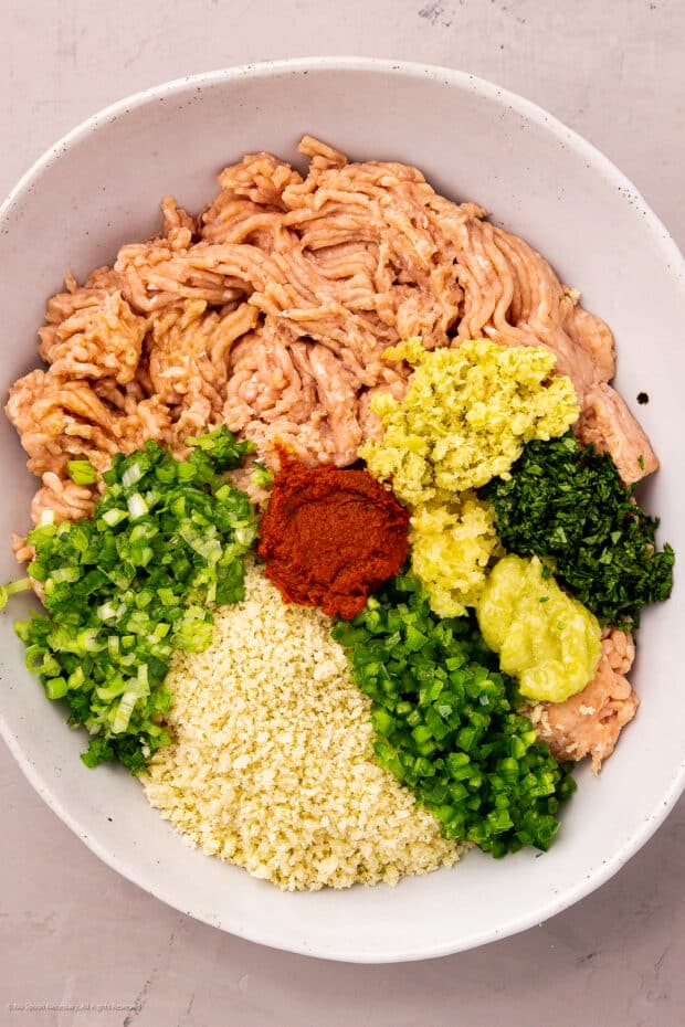 Overhead photo of the ingredients for Thai chicken meatballs in a large mixing bowl.