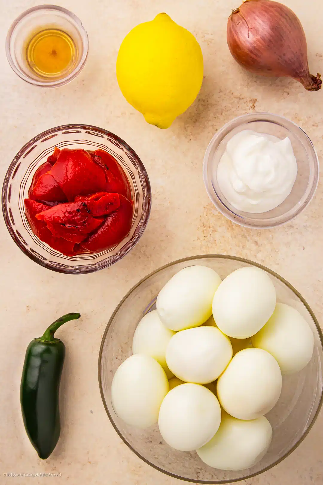 Overhead photo of hard boiled eggs, red bell pepper, greek yogurt, shallot and honey to make creative deviled eggs neatly arranged on a kitchen counter.