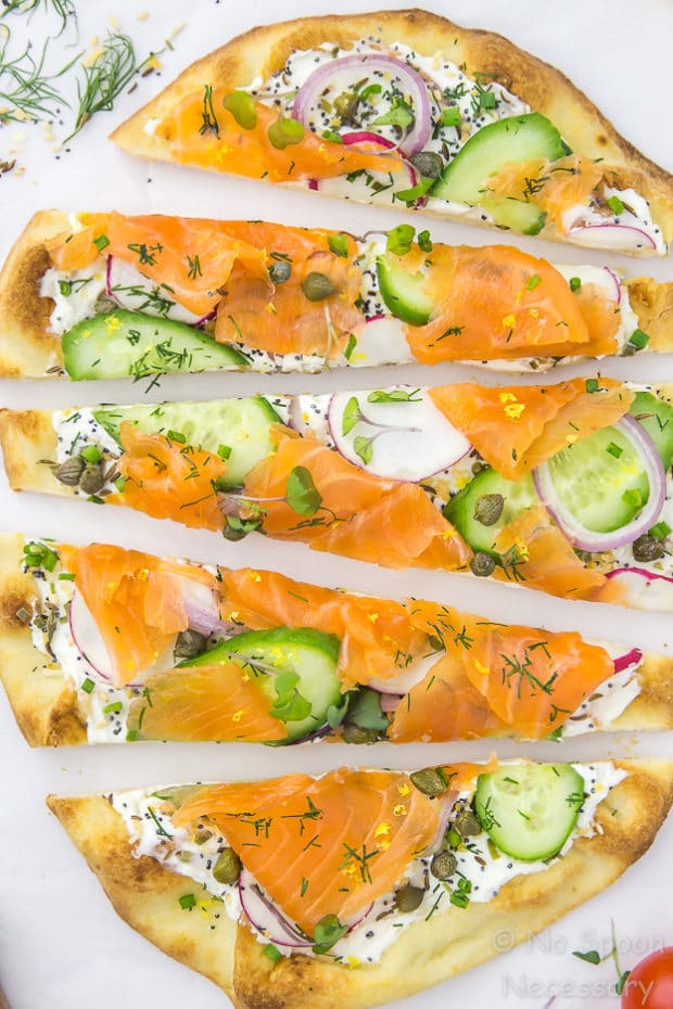 Overhead shot of Loaded Spring Salmon Pizza that has been cut into long slices.