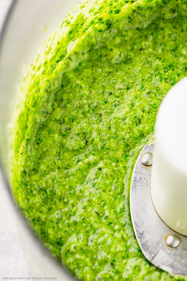 45 degree angle, up close shot of Lemon Basil Pesto in a food processor bowl - the sauce used to dress vegetable couscous.