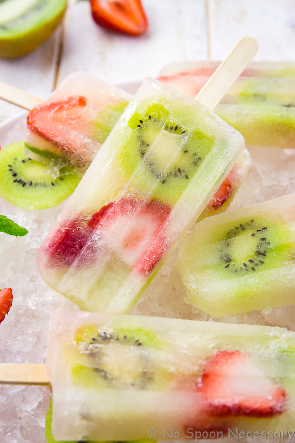 Close up shot of a Strawberry Kiwi Mojito Boozy Popsicle laying on top of other popsicles.