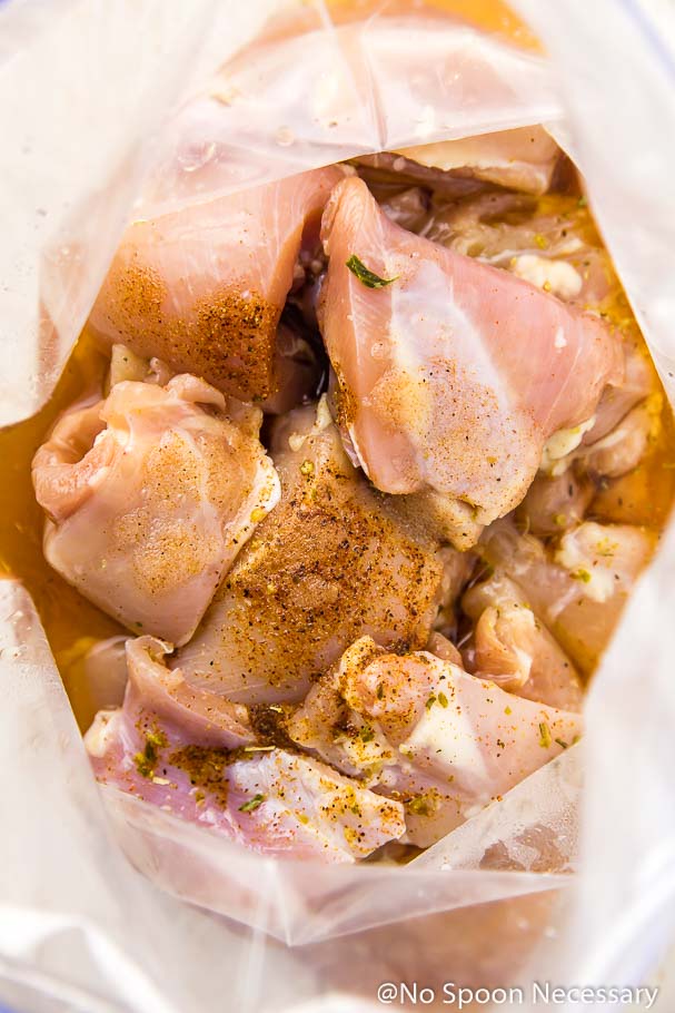 Overhead shot of chicken thighs in a clear zip-closure bag soaking in a margarita marinade topped with fajita seasoning