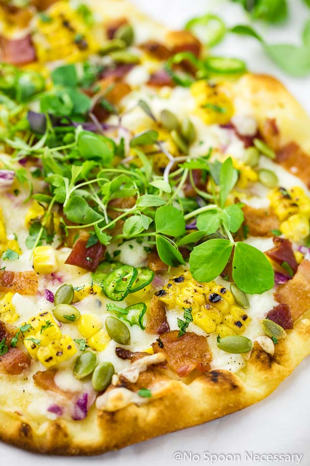 Angled shot of Tex-Mex Charred Corn, Bacon & Jalapeno Pizza topped with microgreens
