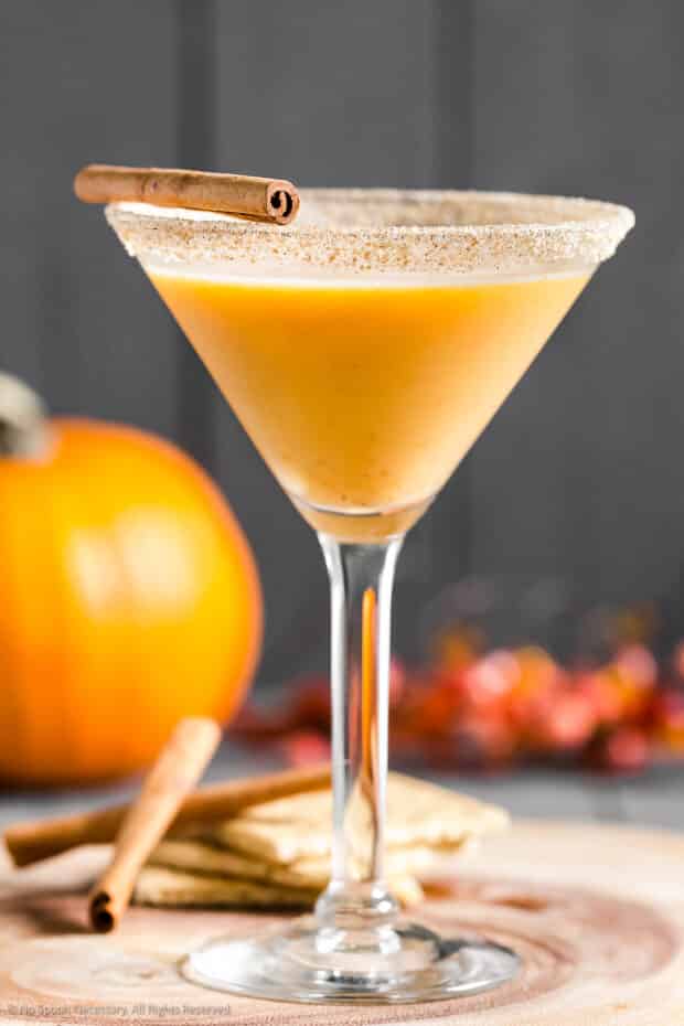Straight on photo of the recipe for pumpkin martini in a martini glass with cinnamon stick.