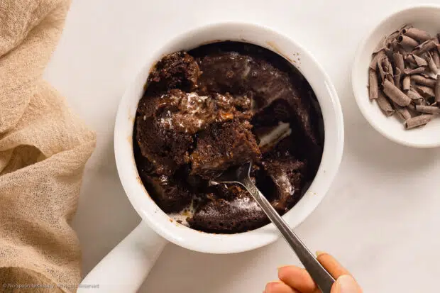Photo of a partially eaten individual chocolate cake in a white coffee cup.